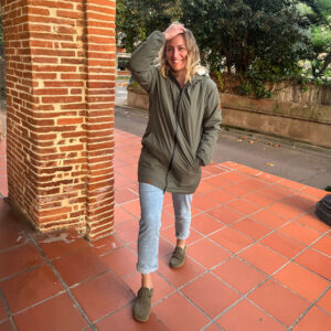 Femme portant une parka verte écoresponsable marchant sur des pavés, style outdoor urbain