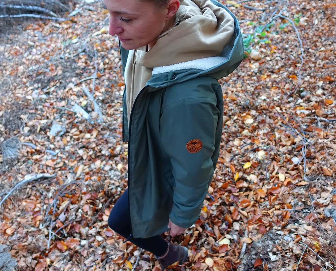Détail d’une parka verte portée en forêt, vêtement écoresponsable