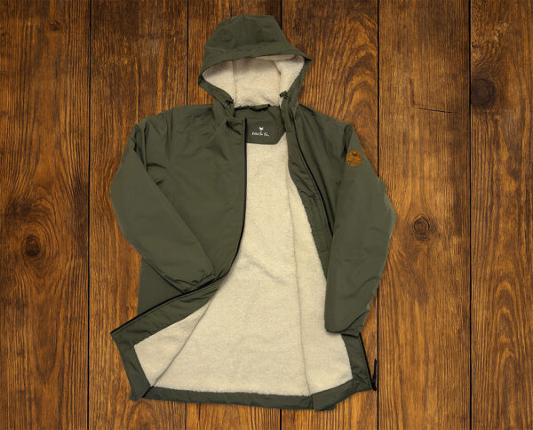 Parka verte doublée présentée à plat sur fond bois, vêtement outdoor durable