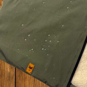 Détail la parka avec zoom sur tissu vert avec patch logo, finition textile responsable doublé sherpa