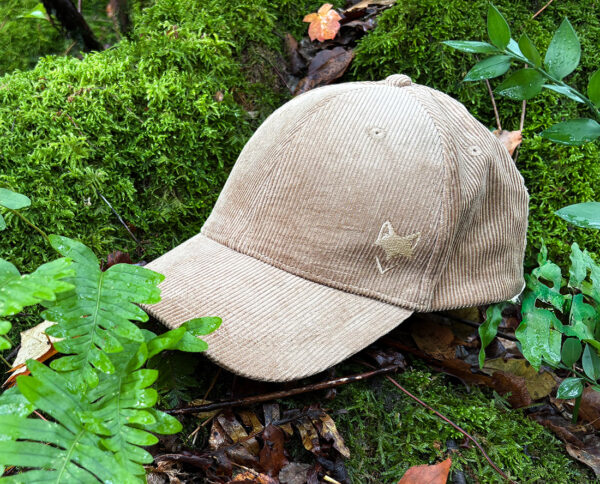 Casquette argile du désert écoresponsable posée dans la végétation, inspiration outdoor.