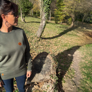 Sweats pliés aux tons naturels présentés sur fond bois, collection outdoor durable