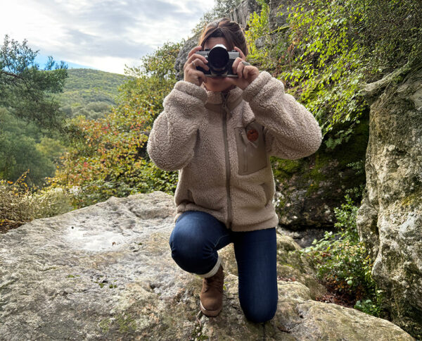 Femme portant une veste sherpa en randonnée sur rochers, esprit aventure slow