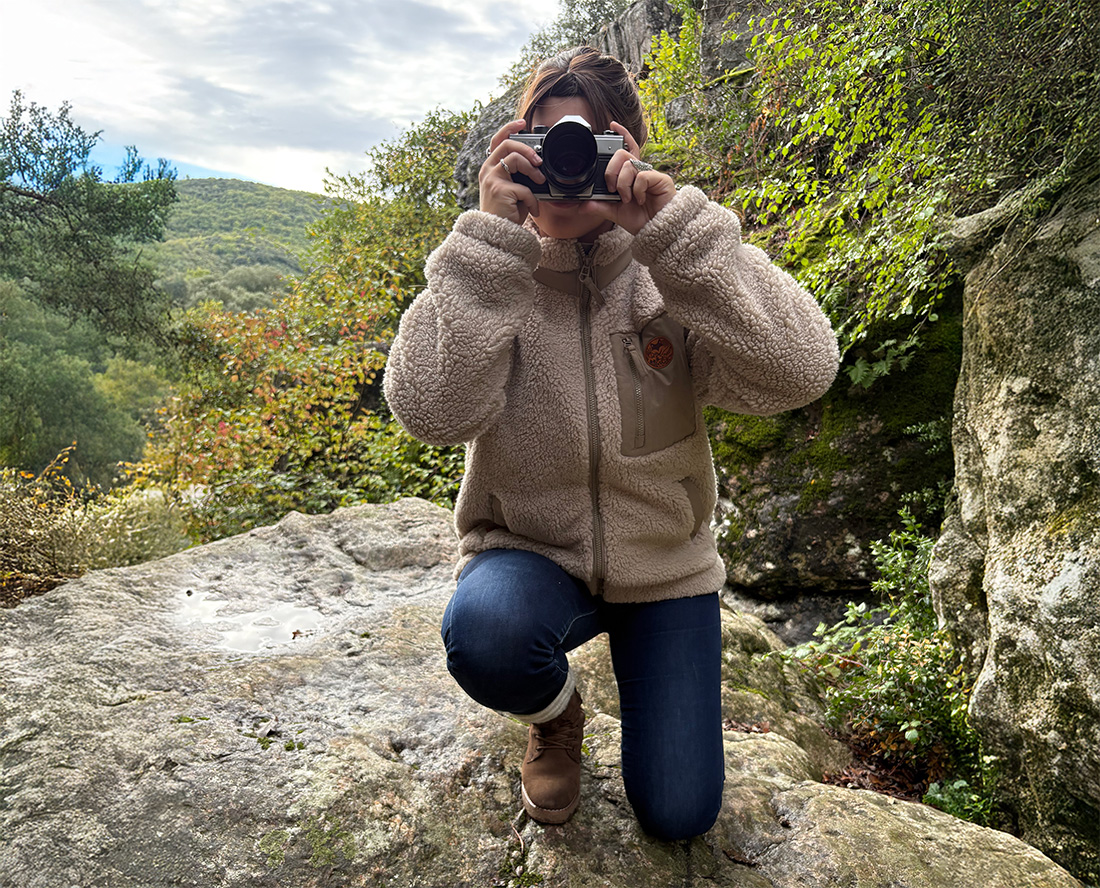 Femme portant une veste sherpa en randonnée sur rochers, esprit aventure slow