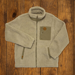 Veste sherpa beige présentée à plat sur fond bois, vêtement outdoor durable