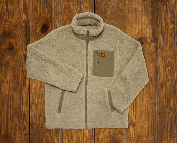 Veste sherpa beige présentée à plat sur fond bois, vêtement outdoor durable