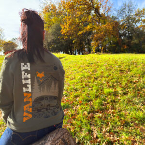 Femme assise dans un champ en sweat vanlife, ambiance automne et liberté