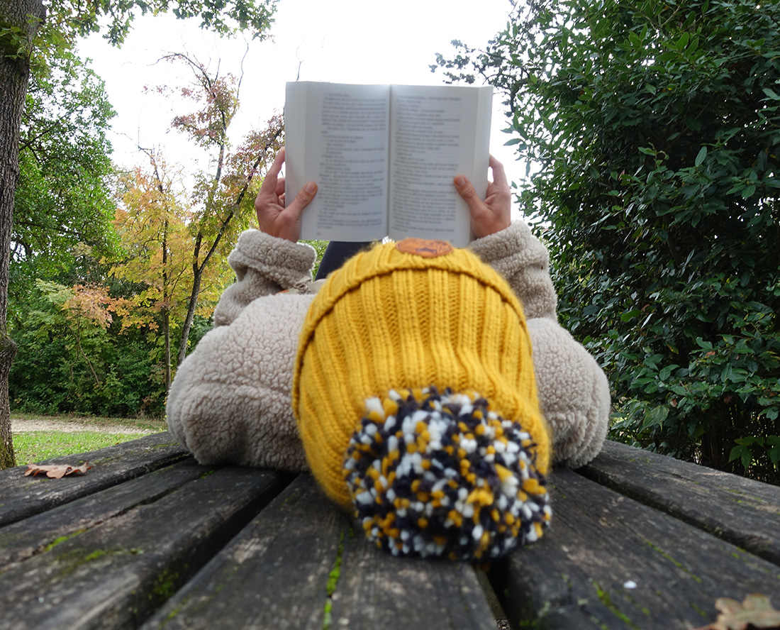 Détail du bonnet ocre vive en matière responsable, porté en extérieur.