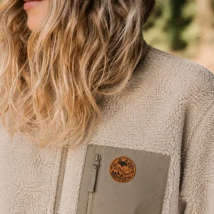 Gros plan sur la texture d’une veste sherpa beige avec écusson, style van life