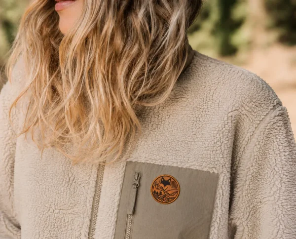 Gros plan sur la texture d’une veste sherpa beige avec écusson, style van life