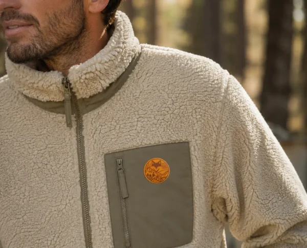 Gros plan sur une veste sherpa beige et son écusson, style van life outdoor