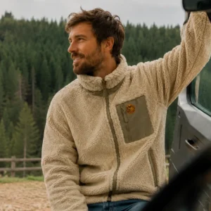 Homme portant une veste sherpa beige lors d’un road trip van life en pleine nature