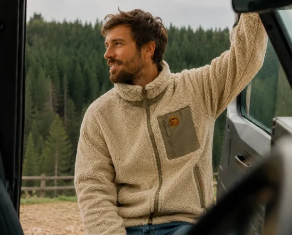 Homme portant une veste sherpa beige lors d’un road trip van life en pleine nature