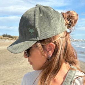 Casquette en velours cotelé écoresponsable portée par une femme, vue de profil en pleine nature.