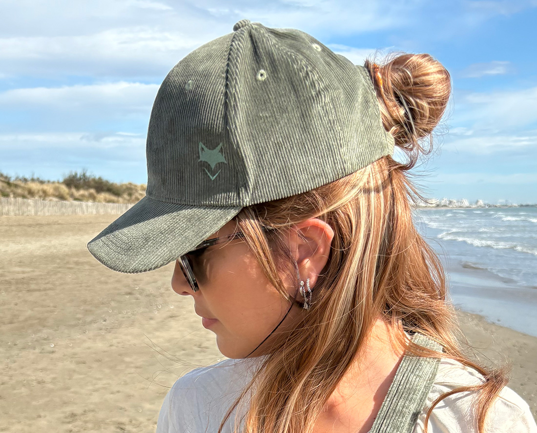 Casquette en velours cotelé écoresponsable portée par une femme, vue de profil en pleine nature.