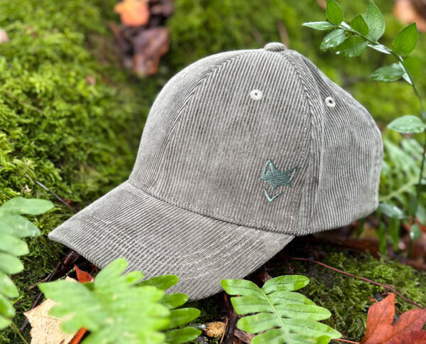 Casquette verdure nomade zoom sur logo brodé écoresponsable posée dans la végétation, inspiration outdoor.