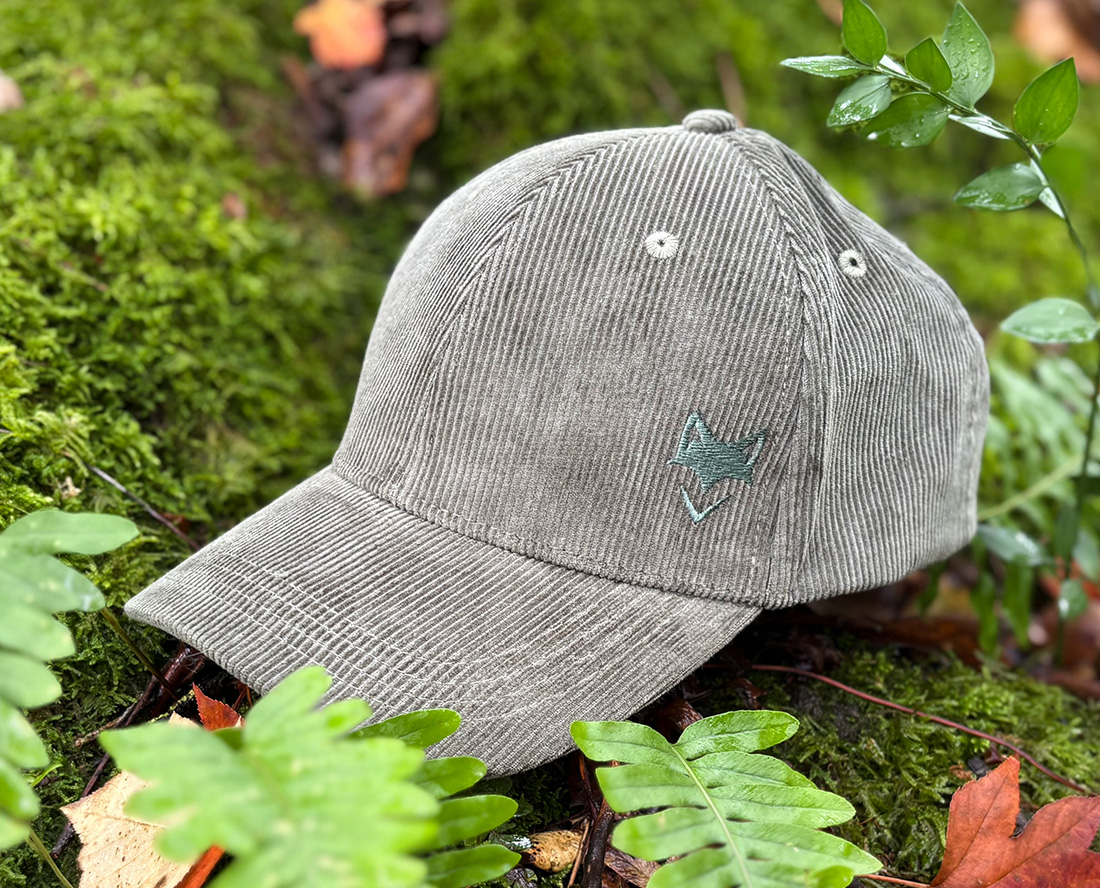 Casquette verdure nomade zoom sur logo brodé écoresponsable posée dans la végétation, inspiration outdoor.