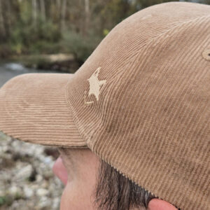 Casquette velours cotelé avec logo brodé, portée en bord de rivière.