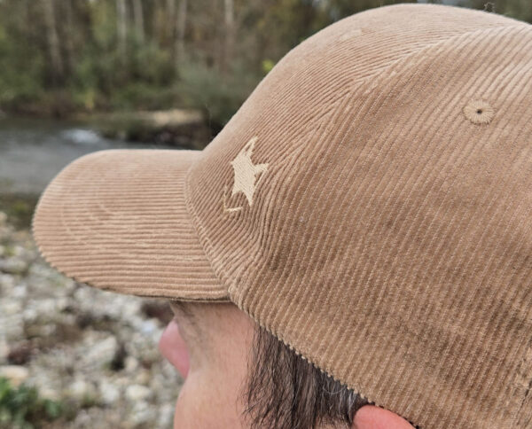 Casquette velours cotelé avec logo brodé, portée en bord de rivière.