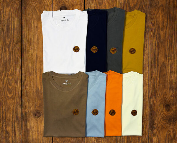 Sélection de t-shirts pliés présentés sur fond bois, collection vanlife durable