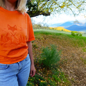Femme en t-shirt orange au bord d’un lac, connexion à la nature