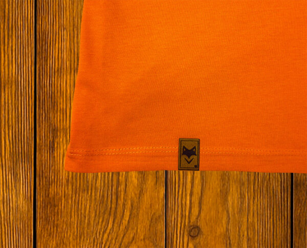 Gros plan sur ourlet et étiquette d’un t-shirt orange en coton bio