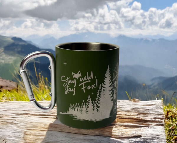 Tasse mousqueton vanlife posée sur un bout de bois devant un paysage naturel