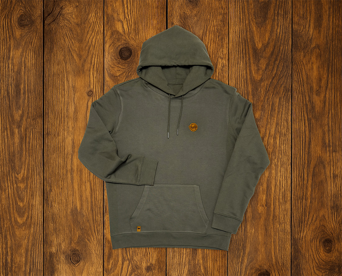 Sweat à capuche vert kaki présenté à plat sur fond bois, esprit vanlife