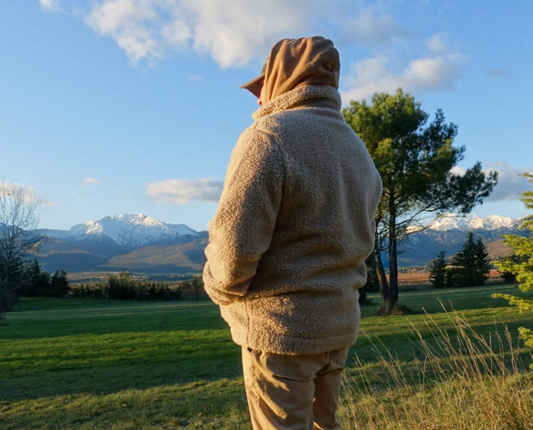 Silhouette en veste sherpa écoresponsable observant la nature au coucher du soleil