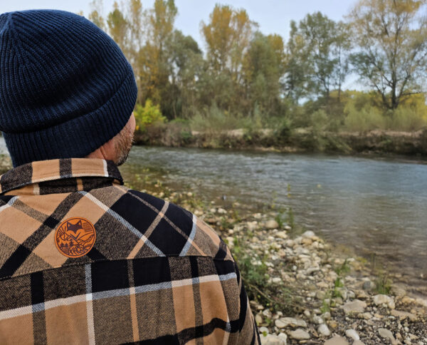 Personne au bord d’une rivière portant une veste outdoor bucheron doublé sherpa, ambiance vanlife slow