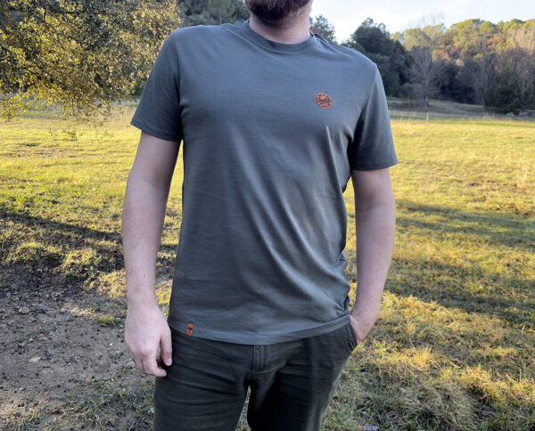 Homme portant un t-shirt de couleur verdure nomade écoresponsable avec logo minimaliste sur la poitrine.