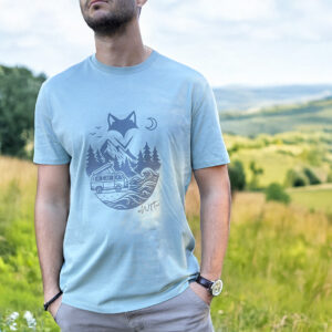 Homme portant un t-shirt rivière alpine vanlife dans un paysage vallonné.