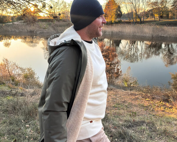 Homme en veste et sweat outdoor au bord de l’eau, style vanlife automnal