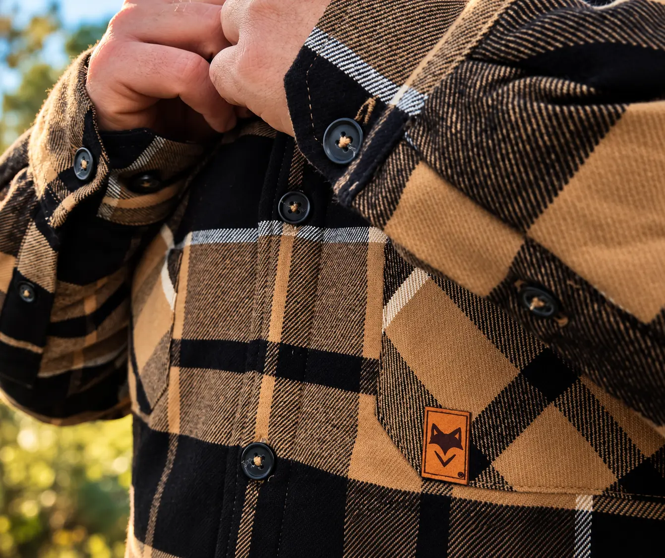 Détail des boutons et de la poche d'une chemise sherpa homme à carreaux beige et noire