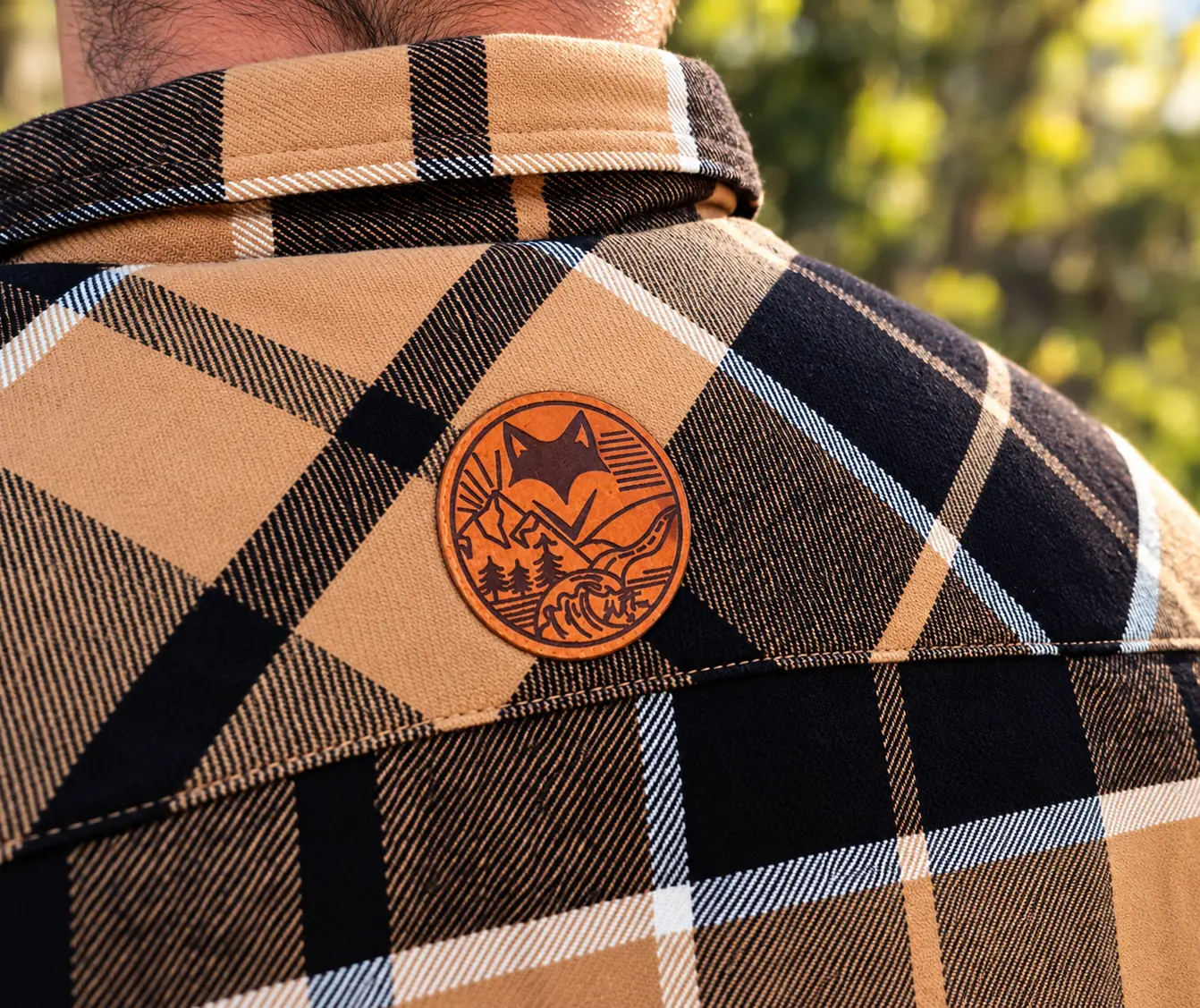 Détail du col et du logo d'une chemise sherpa homme à carreaux beige et noire