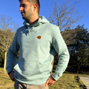 Homme portant un sweat couleur rivière alpine écoresponsable avec logo discret sur la poitrine.