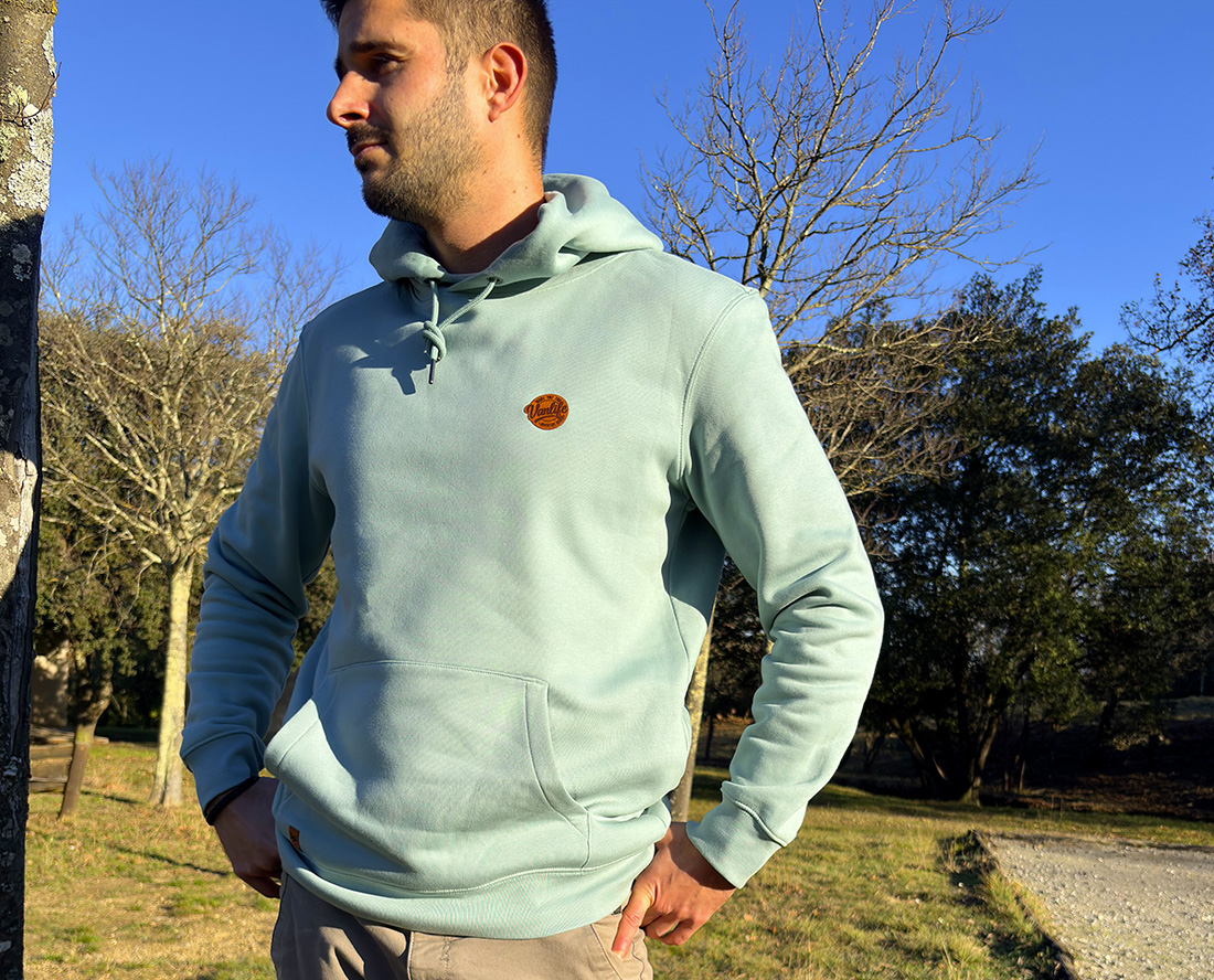 Homme portant un sweat couleur rivière alpine écoresponsable avec logo discret sur la poitrine.