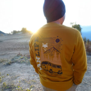 Homme de dos portant un sweat ocre vive recyclé vanlife au lever du soleil.
