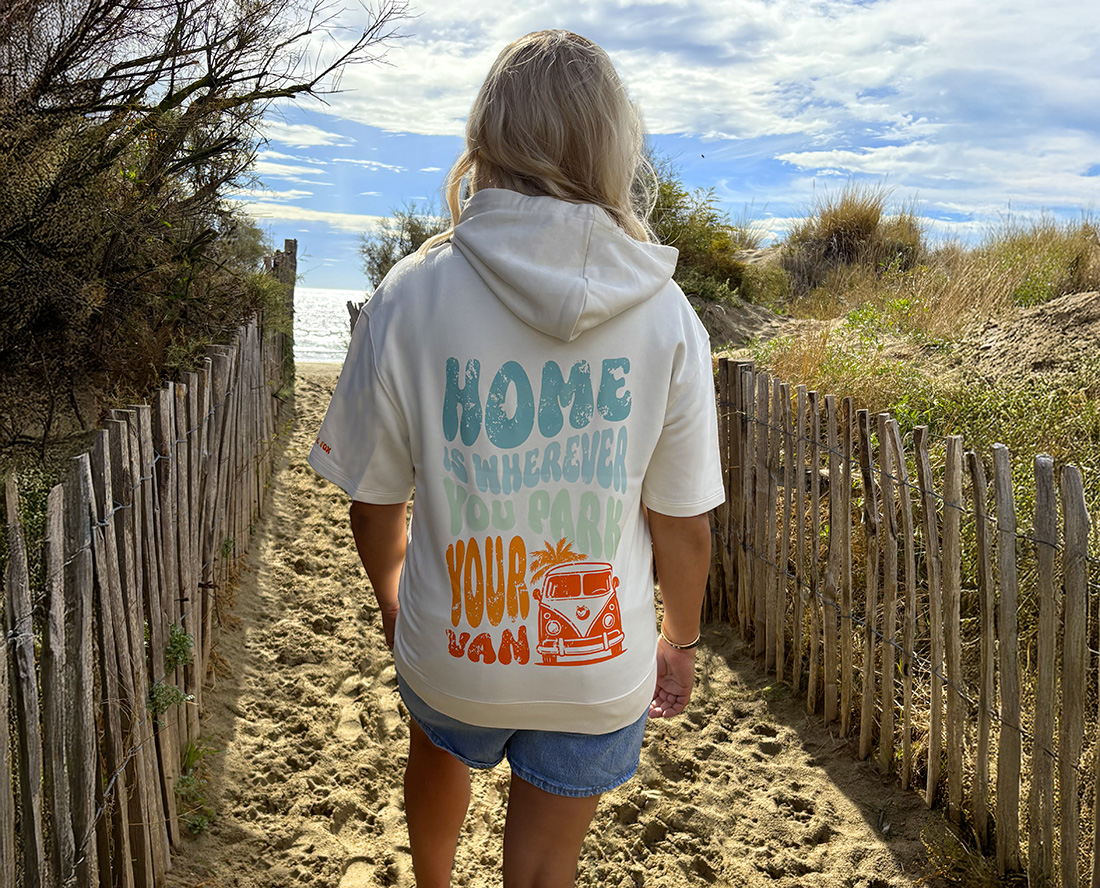 Dos d’un sweat manches courtes blanc vanlife porté sur un sentier en bord de mer, lifestyle outdoor