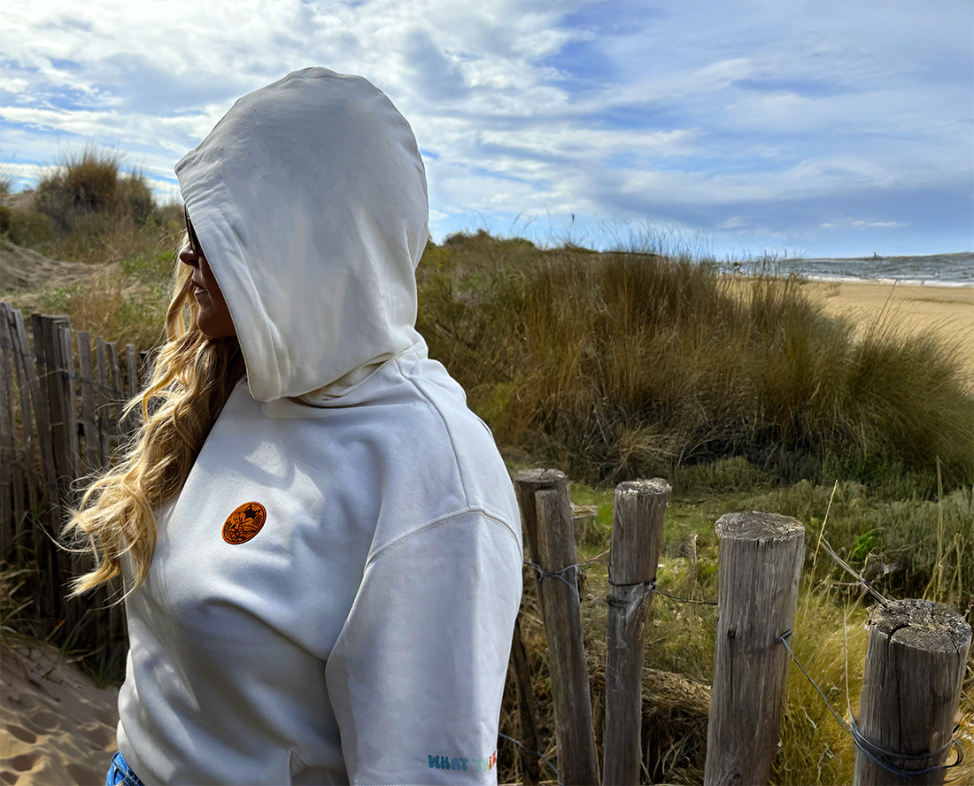 Femme de dos en sweat manches courtes à capuche blanc face à un paysage naturel