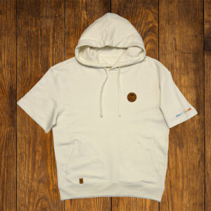 T-shirt blanc à capuche présenté à plat sur fond bois, vêtement lifestyle durable