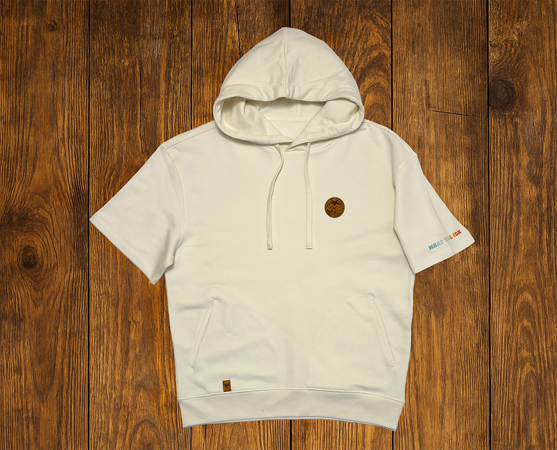 T-shirt blanc à capuche présenté à plat sur fond bois, vêtement lifestyle durable