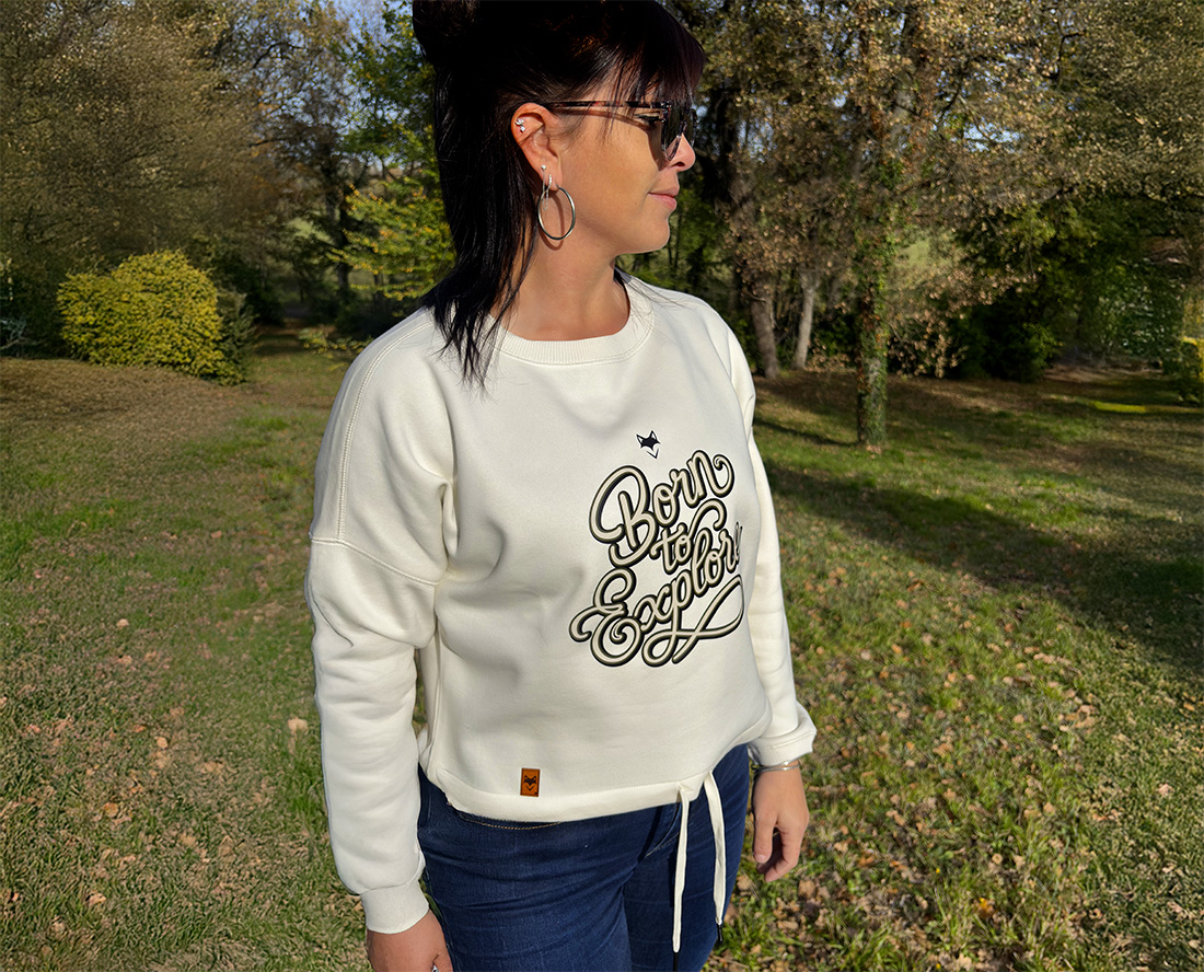 Femme portant un sweat vanlife blanc en extérieur, style outdoor casual et responsable
