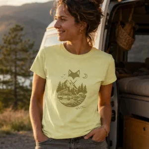 femme devant son van ouvert porte un t-shirt van life jaune pâle en regardant le paysage