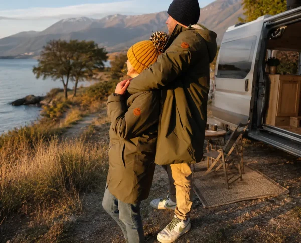 couple portant la parka kaki doublé sherpa en bord de lac lors d'un road trip en van