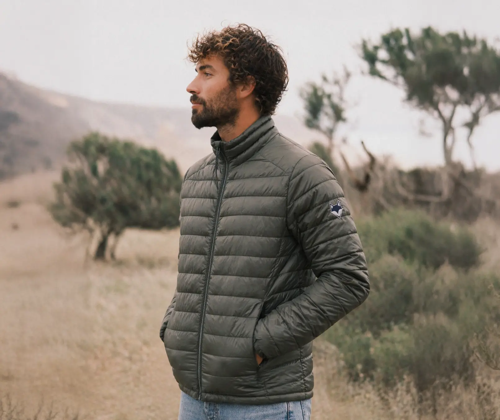 homme dans un champs d'olivier dans le sud de la france portant la doudoune Sirius legère et entierement recyclé.