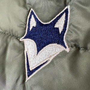 gros plan sur la broderie du logo what the fox sur la manche de la doudoune recyclé