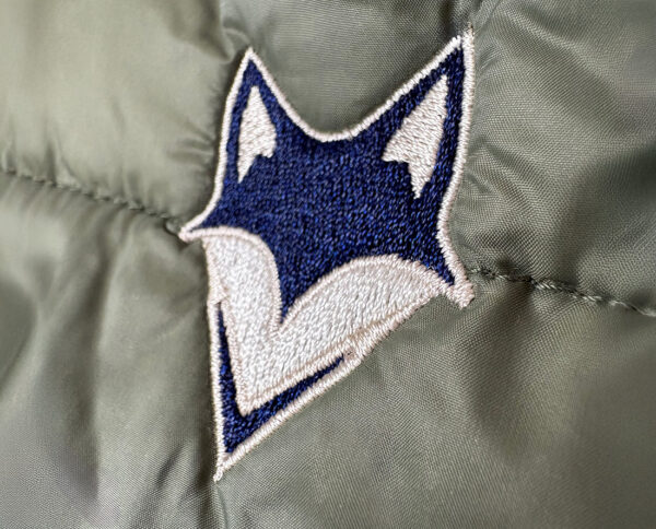 gros plan sur la broderie du logo what the fox sur la manche de la doudoune recyclé