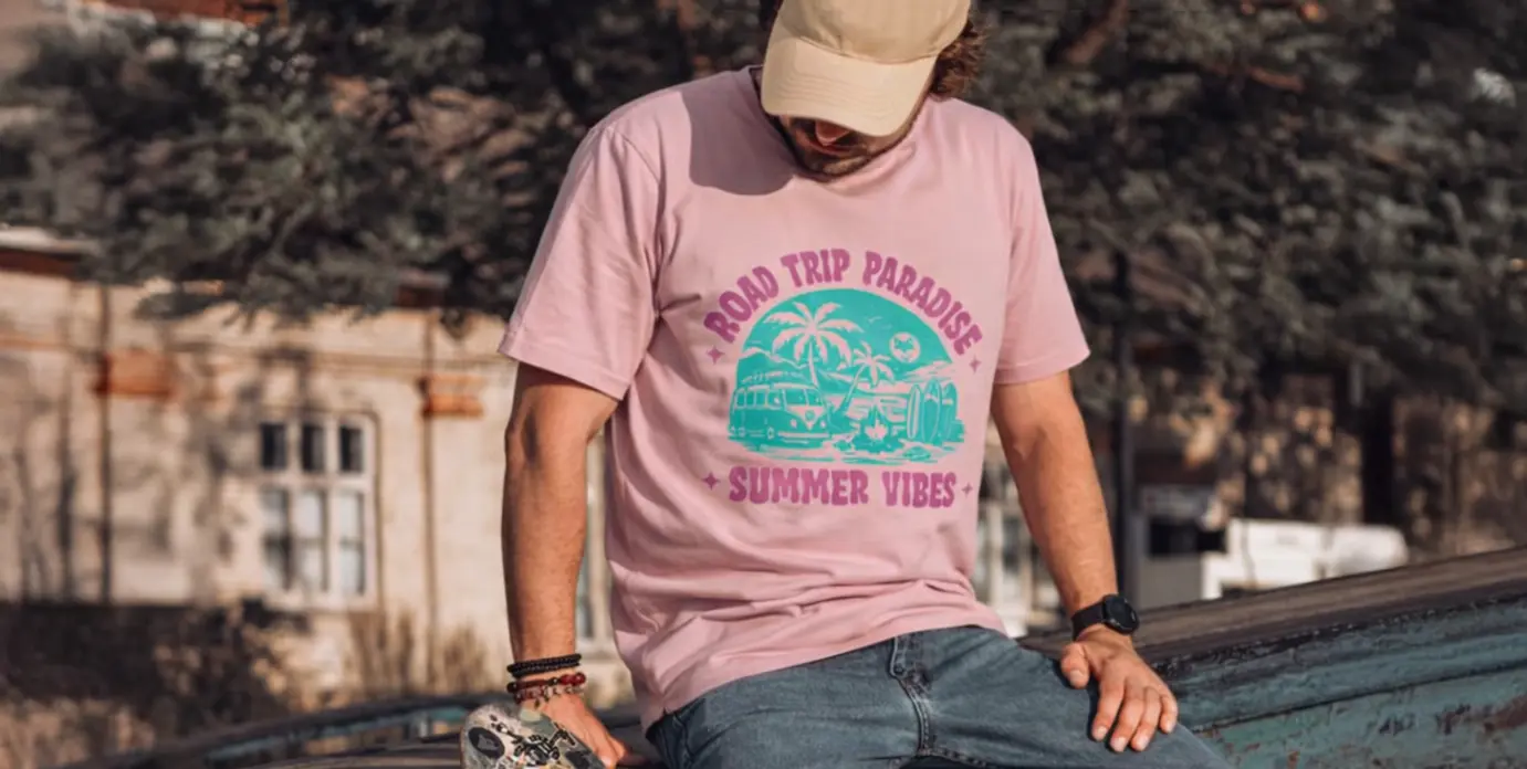 homme assis portant un t-shirt rose pale avec motif van life