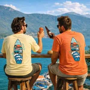 deux homme en t-shirts van life assis face à un lac de montagne entrain de faire l'apéritif